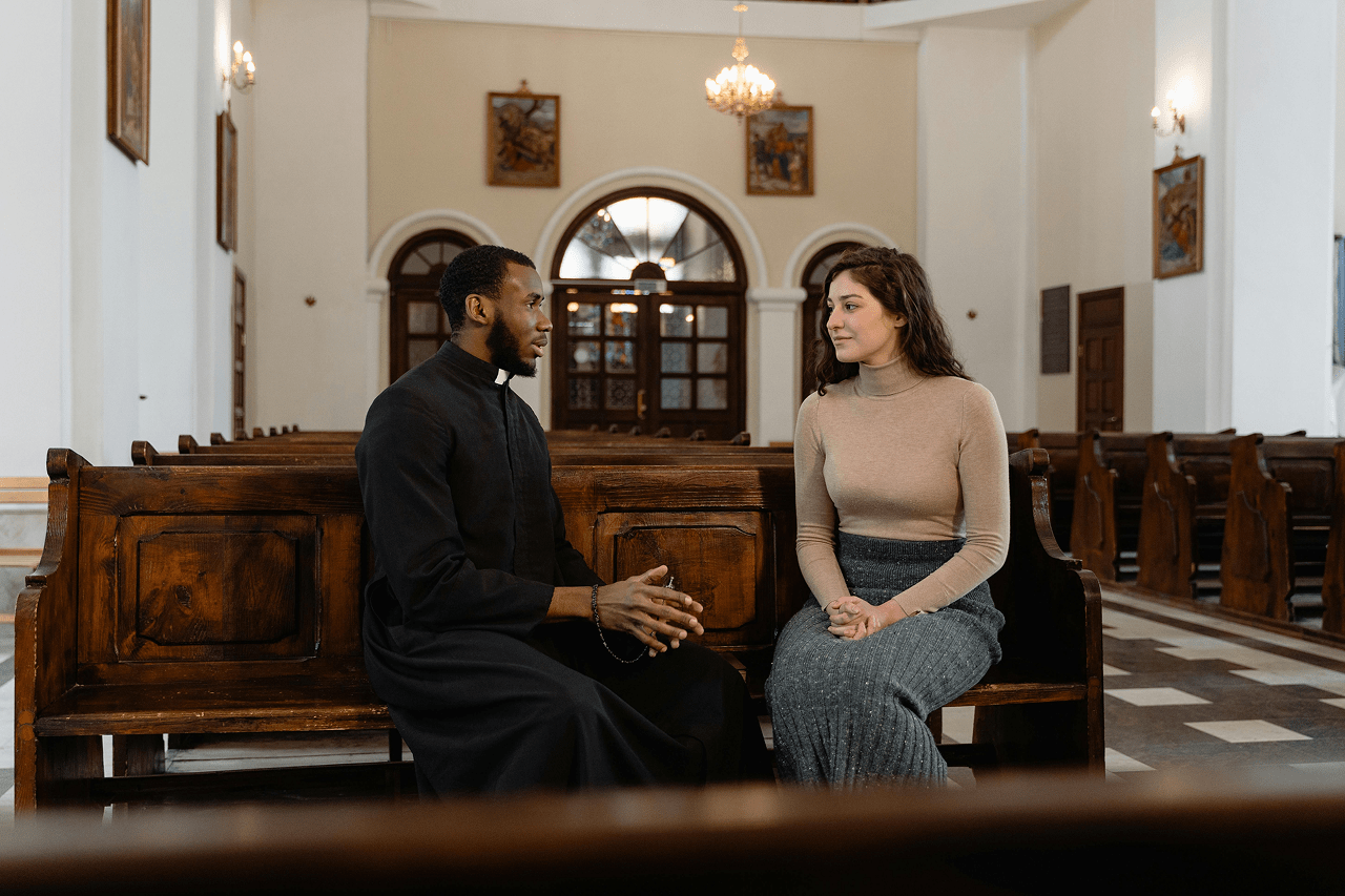A pastor talking with a member in a pew